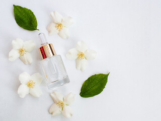 Obraz na płótnie Canvas Jasmine essential oil (tincture, remedy, infusion). Glass bottle with fresh jasmine flowers on a white background. Flower essential oil. Phytotherapy. View from above