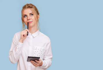 Portrait of an attractive young blonde woman with blue eyes working on a tablet. A young female entrepreneur freelance designer pondered the project, blue isolated background.