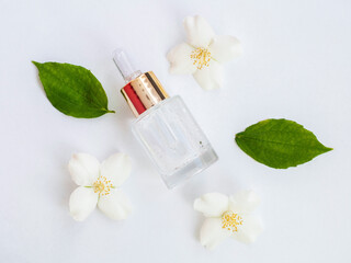 Jasmine essential oil (tincture, remedy, infusion). Glass bottle with fresh jasmine flowers on a white background. Flower essential oil. Phytotherapy. View from above