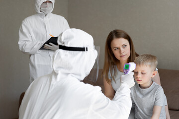 Coronavirus. Doctor checks boy's body temperature using infrared forehead thermometer gun for virus...