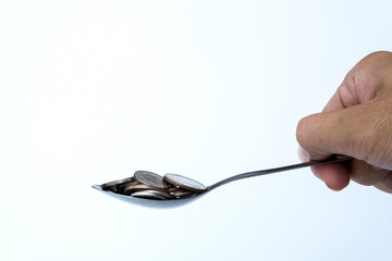 The man was scooping the coin up with a metal spoon on white background