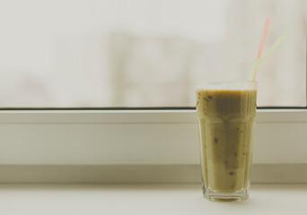 Green healthy smoothie in transparent glass on white background. Copy space on left side. 