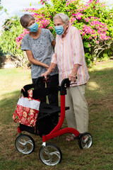 Carer helping elderly frail lady while going for a walk