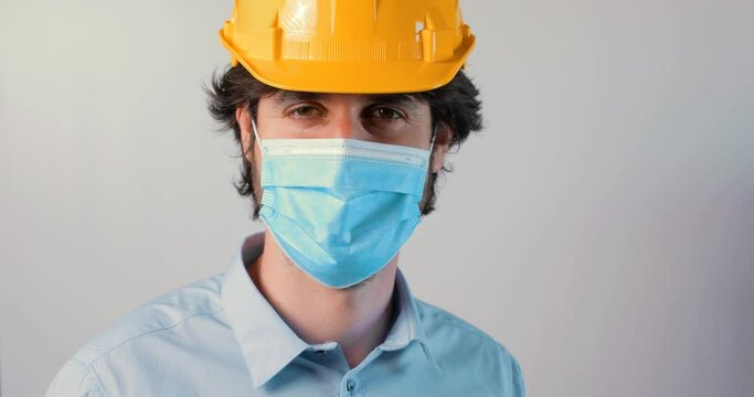 Ingegnere o architetto con casco giallo e mascherina chirurgica per coronavirus