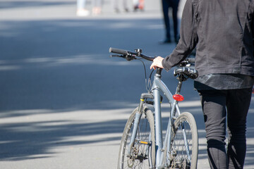 A guy is roll a bicycle along a deserted pedestrian city street in a sunny day.