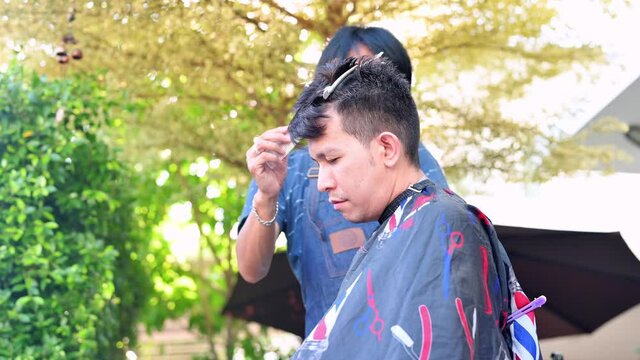 Thai people making haircut at home garden. Learning online barber courses during lock down for new occupation. New normal life after Covid-19 outbreak pandemic situation.