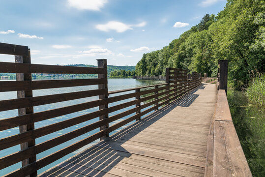 Wooden boardwalk on water. Lake Comabbio, Italy and the pedestrian cycle track around the lake