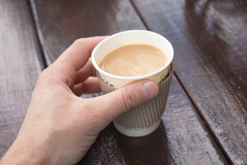 Hand holds a glass of natural coffee with milk.
