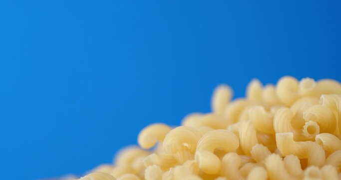A handful of dry pasta of cavatappi rotates slowly.