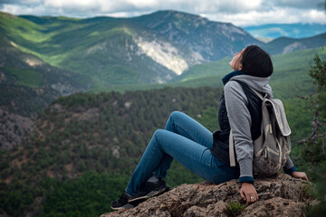 Young traveling woman on the top of the mountain cliff