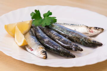 plate of fresh sardines with parsley and lemon on the plate