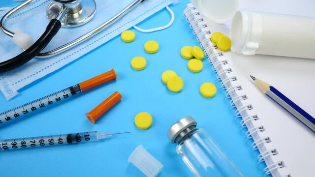 Heap of Pills, Syringe for Insection, Stethoscope and Face Mask on blue background. Health care, doctor, clinic or hospital concept. Medical Equipment