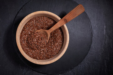 Flax seeds and a wooden spoon with bowl on a dark table. Healthy food and drink concept. Top View.