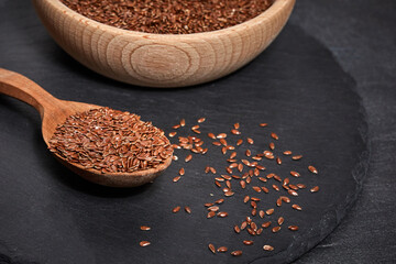 Flax seeds and a wooden spoon with bowl on a dark table. Healthy food and drink concept. Top View.