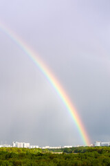 rainbow over green city park and apartment houses on horizon on spring day