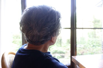 窓際に座って外を眺める日本のおばあちゃん