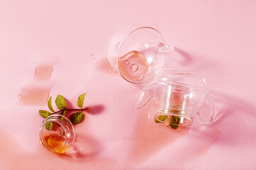 thrown glass teapot and spilled tea on a pink background. abstract