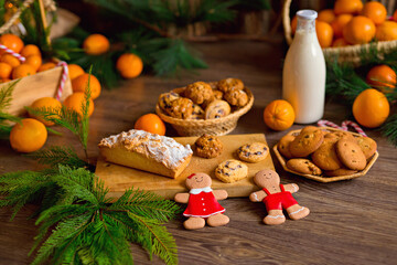 Christmas gingerbread cookies, tangerines, branches of a Christmas tree with garlands on a wooden background. A Christmas background with space for text. Happy Christmas morning.