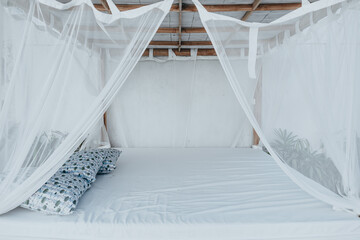 Gazebo with a wooden bed under a mosquito grid on a outside