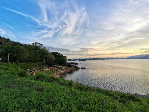 A beautiful landscape capture of nature photography. Evening sky full of shady white clouds is amazing to see. Green grass and grey rocks on the left side give a better mixture of colors.