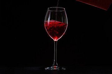 A glass of red vine on black background. Wine glass on dark table.