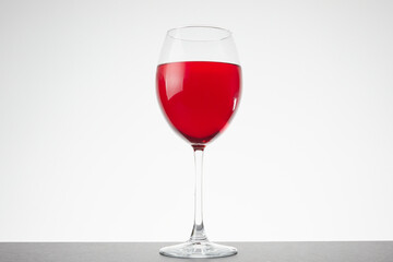 A glass of red vine on white background. Wine glass on dark table.