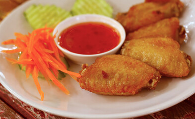 Fried chicken with sauce on a white plate set on a wood table.