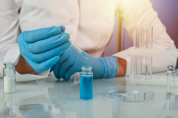 laboratory assistant dropping reagent from a dropper into a flask on blue background