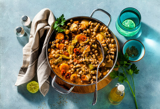 Black-eyed Pea Vegan Chili in a metal pan on a wooden stand on a blue background