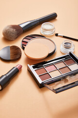 powder with professional face makeup brushes and eyeshadows with lipstick on beige background, close view, beauty concept 