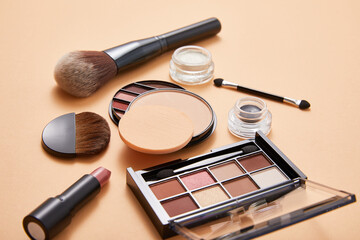 powder with professional face makeup brushes and eyeshadows with lipstick on beige background, close view, beauty concept 