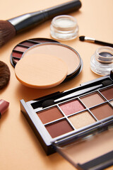 powder with professional face makeup brushes and eyeshadows with lipstick on beige background, close view, beauty concept 