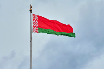 Fototapeta na wymiar The national flag of the Republic of Belarus on a background of cloudy sky..