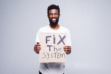 Young african man holding a cardboard poster with the message text Fix the system isolated on white...