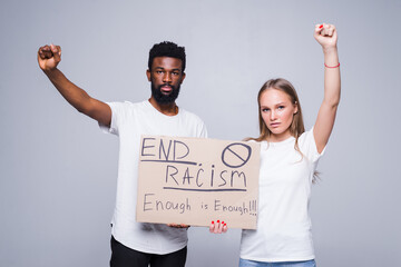 Young african man and coucasian woman holding a cardboard poster with the message text END RACISM...