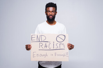 Young african man and coucasian woman holding a cardboard poster with the message text END RACISM...