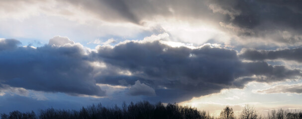 Horizontal panorama of the evening pre-thunderstorm sky and sun. Sun rays through the clouds.