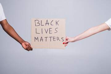 protest white and black hands holding cardboard poster with message text BLACK LIVES MATTERS...