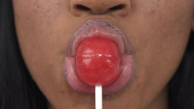 Close-up of a woman eating sweet lollipop. Focus on lips. Isolated, on white background