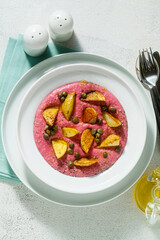 summer dish with pink hummus from cannellini beans and beets with fried potatoes and capers in a plate on the table