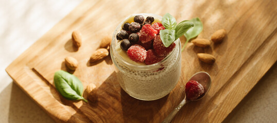 Obraz na płótnie Canvas Chia seed pudding with berries on wooden background. banner for website
