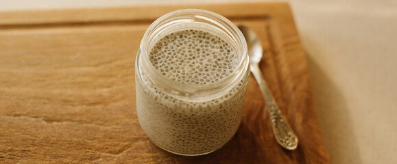 Dessert bowl of tasty chia seed pudding on wooden table on white