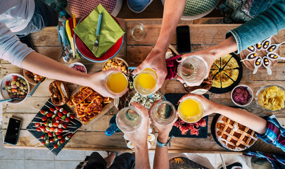 Table with food and friends clinking and toasting together in friendship having fun and celebrate - concept of friends caucasian people have lunch and enjoy the group