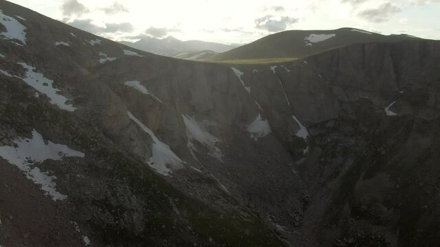 Aerial shot of snow on rocky mountain against sky, drone flying forward over natural landscape - Mount Evans, Colorado