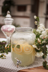 Lemonade in glass jug on wooden table outdoors. Summer refreshing drink.