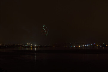 Beautiful firework on night sky in tromsoe city with bridge, cathedral and colorful reflection on the cold fjord water surface on new years eve