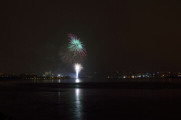Beautiful firework on night sky in tromsoe city with bridge, cathedral and colorful reflection on the cold fjord water surface on new years eve