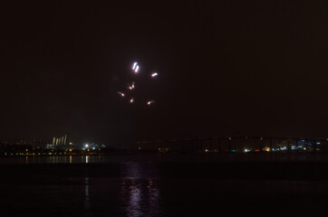 Obraz premium Beautiful firework on night sky in tromsoe city with bridge, cathedral and colorful reflection on the cold fjord water surface on new years eve