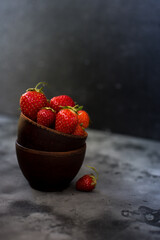 Bowls with ripe fresh strawberry on dark background