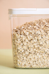 Plastic transparent container with oatmeal on a green background.